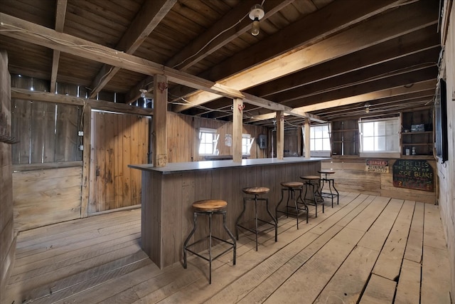 interior space with light hardwood / wood-style flooring, beam ceiling, wood walls, and wooden ceiling