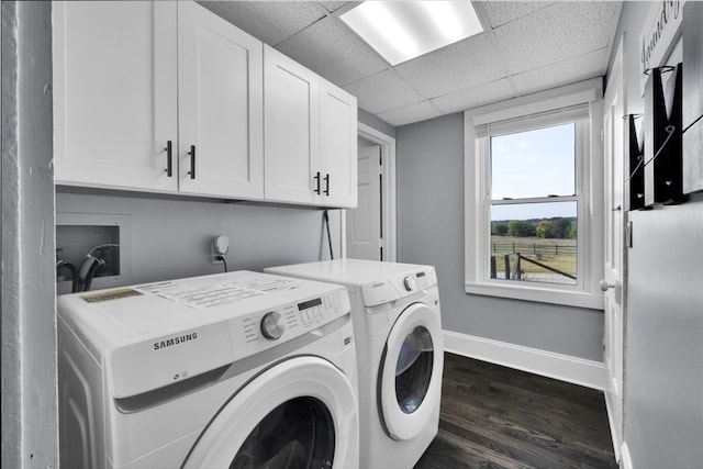 washroom with dark wood-type flooring, washer and dryer, and cabinets