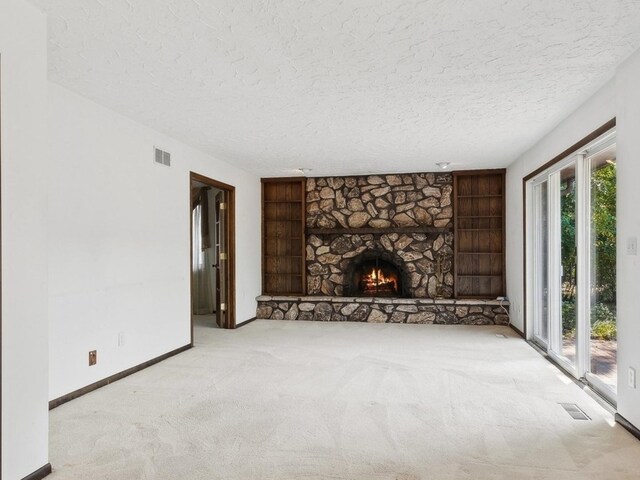 unfurnished living room featuring a textured ceiling, carpet floors, and a fireplace