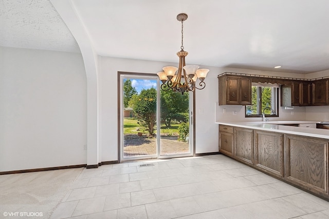 kitchen featuring dark brown cabinets, pendant lighting, an inviting chandelier, and light tile patterned floors