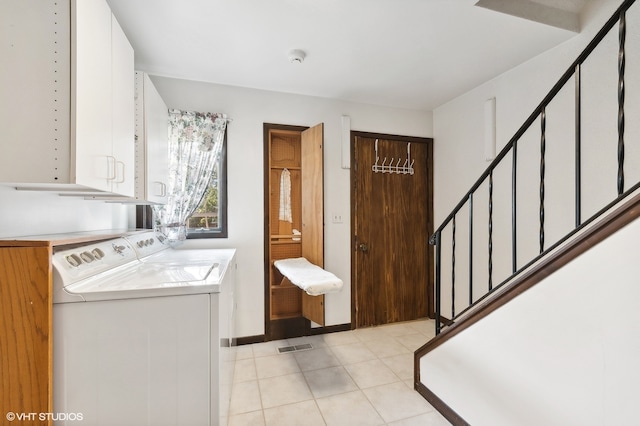 clothes washing area with washer and clothes dryer and cabinets