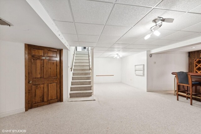 basement featuring a drop ceiling and light carpet