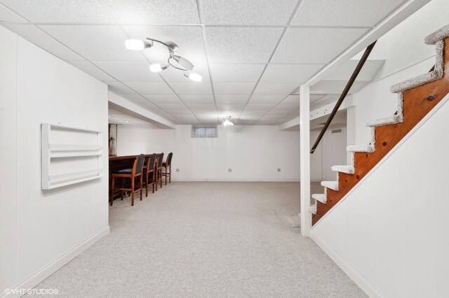 basement featuring a drop ceiling and light colored carpet