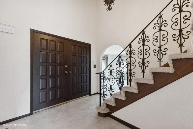 entryway with a towering ceiling and light tile patterned floors