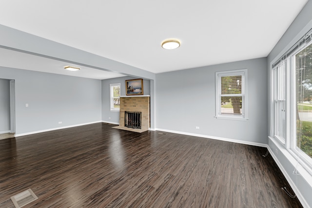 unfurnished living room featuring plenty of natural light and dark hardwood / wood-style floors