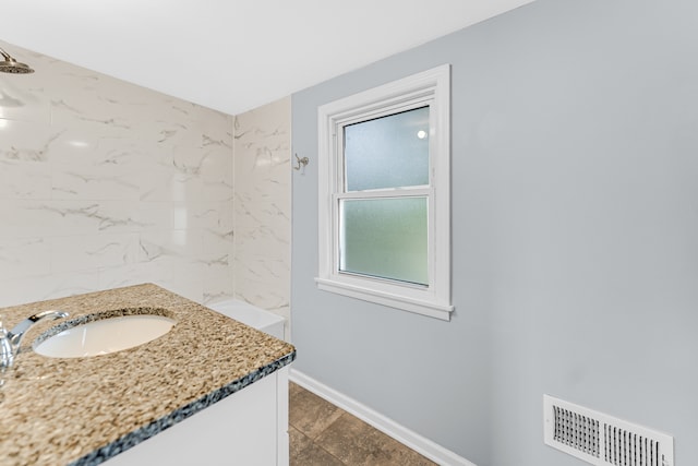 bathroom with vanity, a tile shower, and tile patterned floors