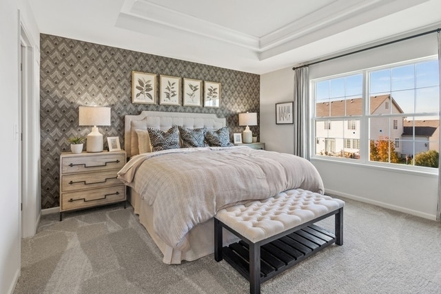 bedroom with a tray ceiling, crown molding, and carpet