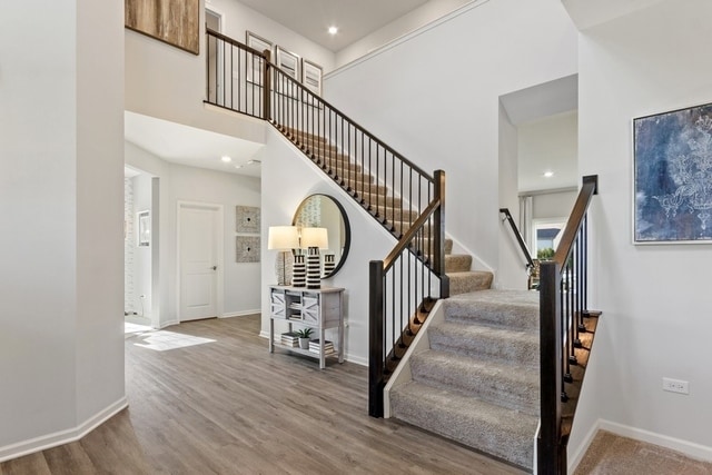 stairway featuring a high ceiling and hardwood / wood-style floors