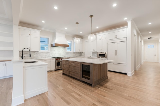 kitchen featuring premium range hood, sink, high quality appliances, a kitchen island, and pendant lighting