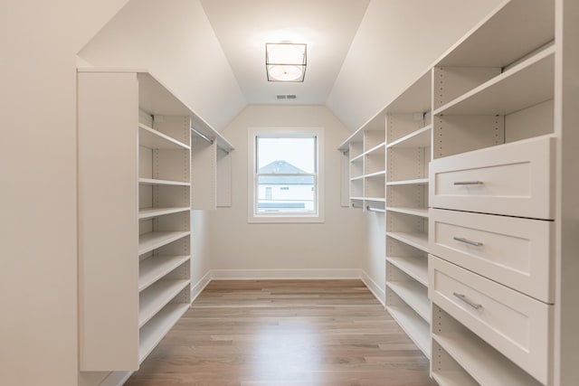 walk in closet featuring vaulted ceiling and light wood-type flooring