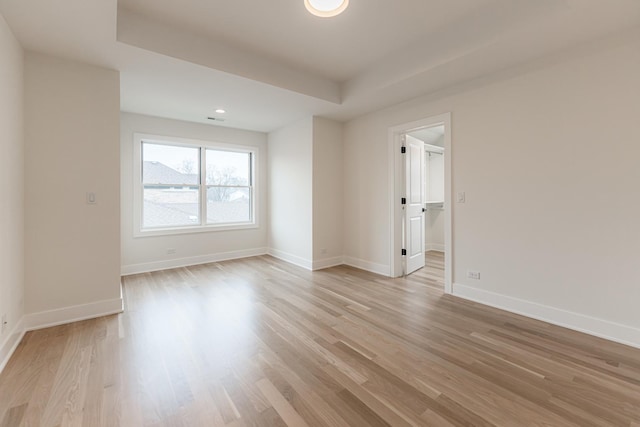 unfurnished room featuring a tray ceiling and light hardwood / wood-style flooring