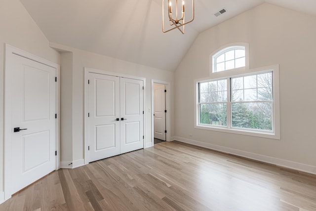 unfurnished bedroom with an inviting chandelier, vaulted ceiling, light hardwood / wood-style floors, and a closet