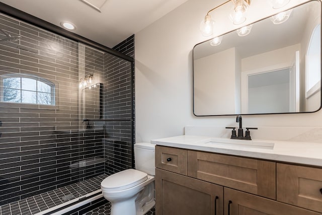 bathroom featuring vanity, toilet, and a shower with shower door