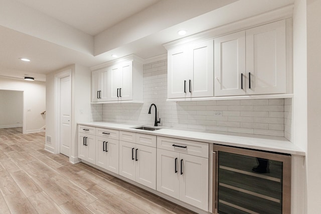 kitchen with white cabinetry, sink, beverage cooler, and backsplash