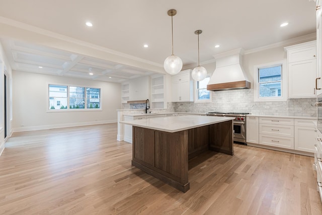 kitchen featuring beamed ceiling, coffered ceiling, a center island, high end stainless steel range, and custom range hood