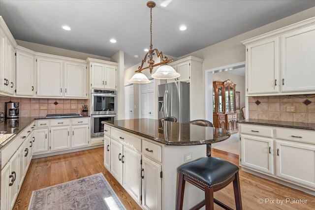 kitchen featuring a center island, hanging light fixtures, tasteful backsplash, light hardwood / wood-style floors, and appliances with stainless steel finishes