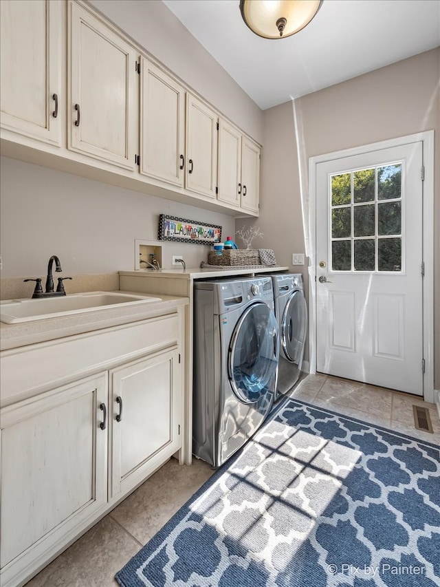 laundry room with cabinets, light tile patterned floors, washing machine and dryer, and sink