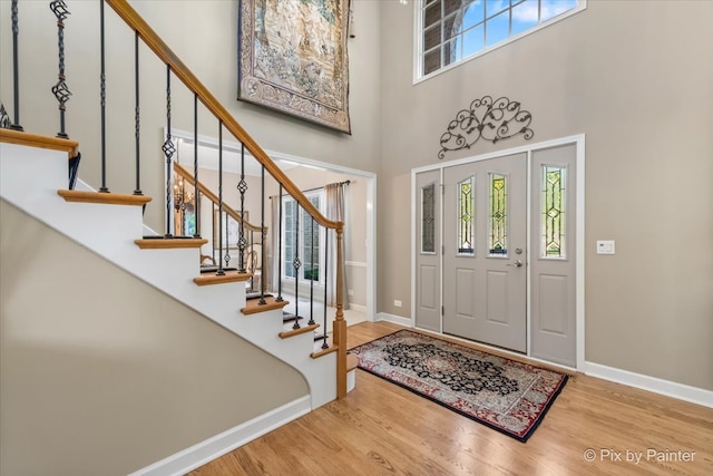 foyer featuring wood-type flooring and a towering ceiling