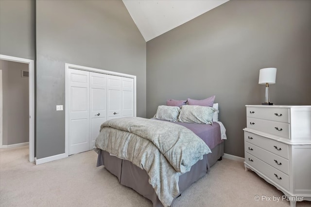 bedroom featuring light colored carpet, high vaulted ceiling, and a closet