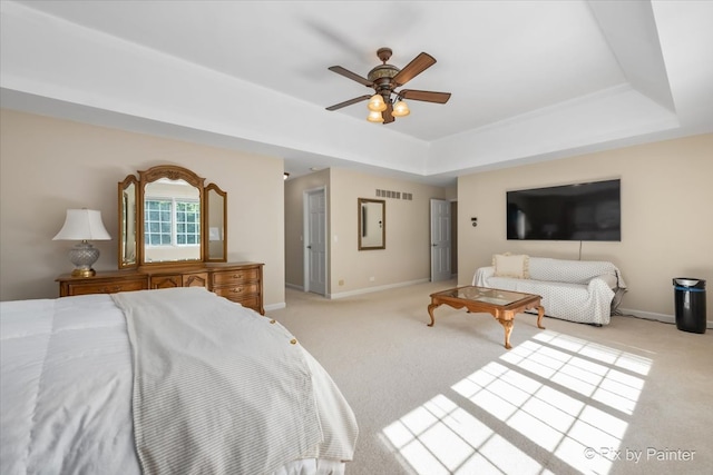 bedroom featuring light colored carpet, ceiling fan, and a tray ceiling