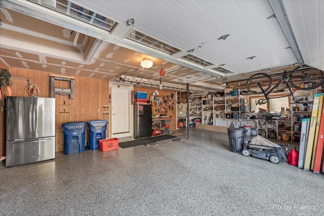 garage featuring a workshop area, stainless steel fridge, and wood walls