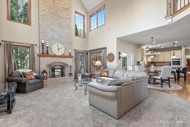 living room featuring a fireplace, a towering ceiling, light wood-type flooring, and a notable chandelier