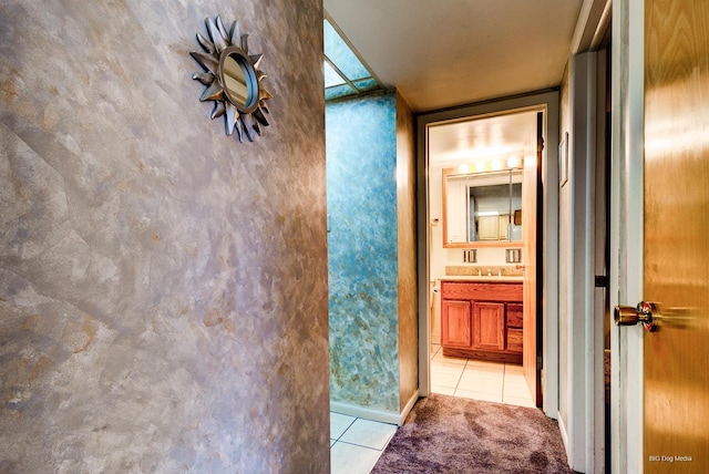 hallway featuring light tile patterned floors and a sink