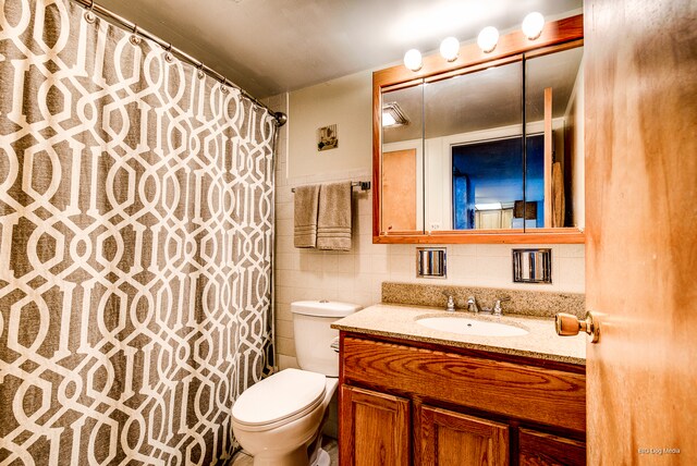 bathroom with tile walls, vanity, and toilet