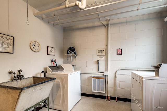 community laundry room featuring concrete block wall, a sink, and washing machine and dryer