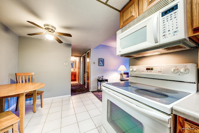 kitchen with white appliances, baseboards, ceiling fan, brown cabinetry, and light tile patterned floors
