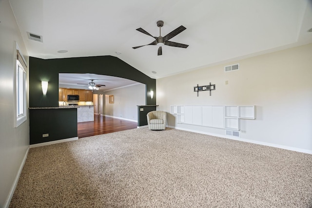 unfurnished living room with ceiling fan, dark carpet, and lofted ceiling