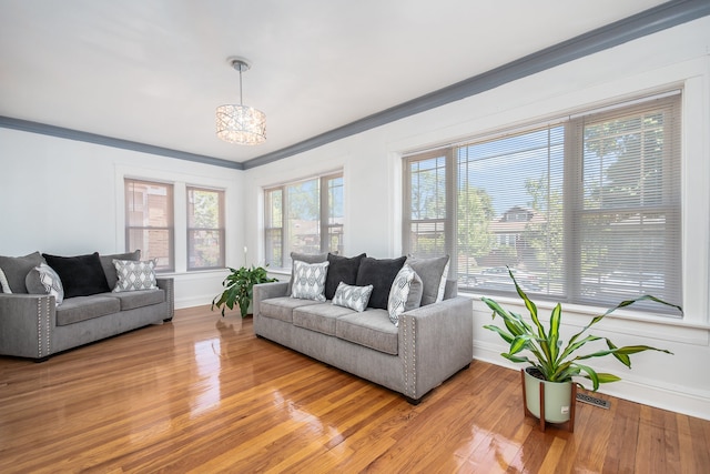 living room with wood-type flooring, ornamental molding, and a notable chandelier