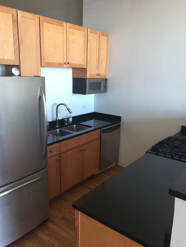 kitchen with dark hardwood / wood-style flooring, stainless steel appliances, light brown cabinetry, and sink