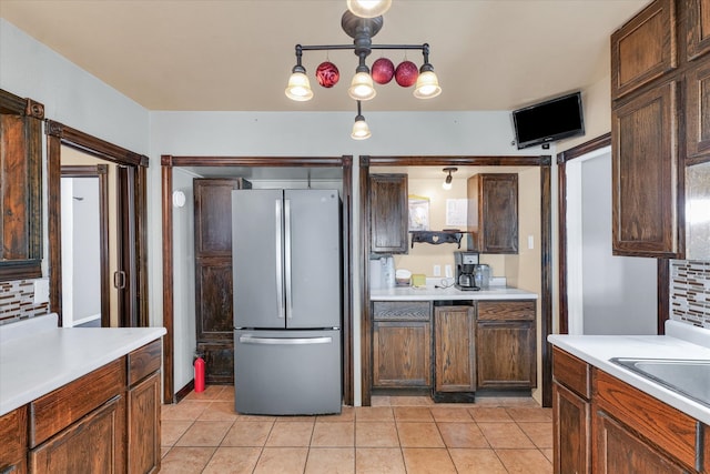 kitchen featuring dark brown cabinetry, stainless steel refrigerator, light tile patterned floors, and hanging light fixtures