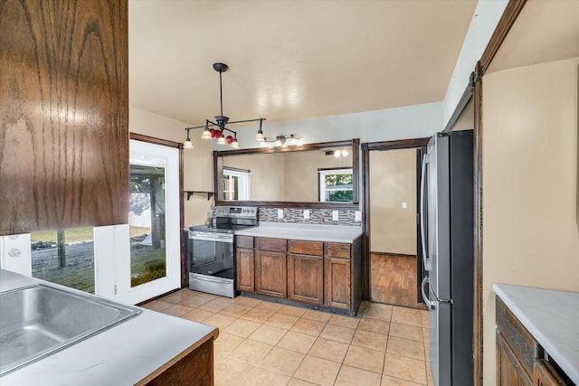 kitchen featuring stainless steel appliances, sink, a barn door, decorative light fixtures, and tasteful backsplash