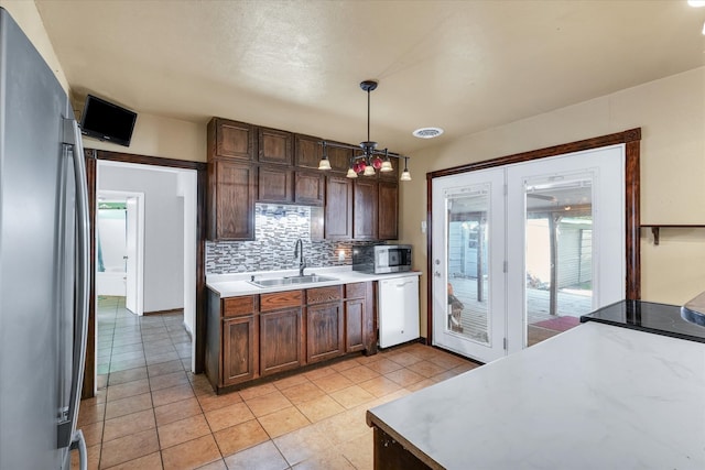 kitchen featuring sink, backsplash, stainless steel appliances, pendant lighting, and light tile patterned floors