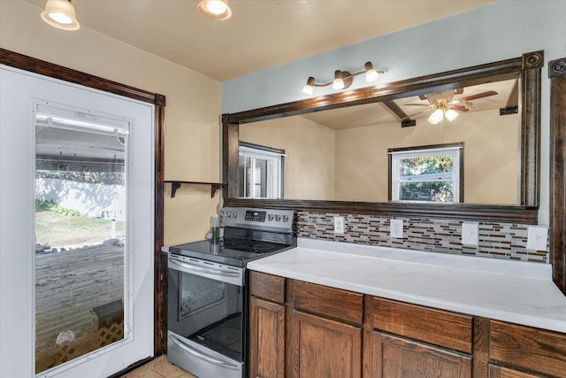 kitchen with light tile patterned floors, electric range, backsplash, and ceiling fan