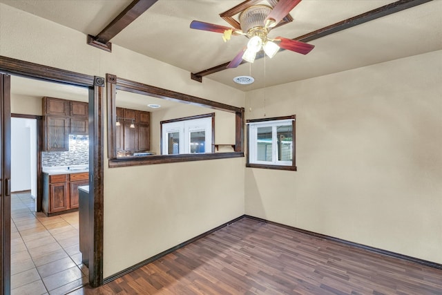 spare room with french doors, ceiling fan, beam ceiling, and light wood-type flooring