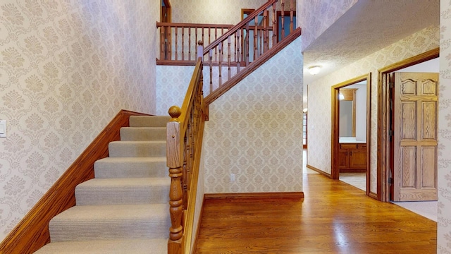 stairway with hardwood / wood-style floors and a textured ceiling