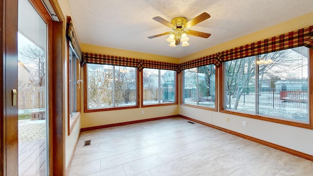 unfurnished sunroom featuring ceiling fan and plenty of natural light