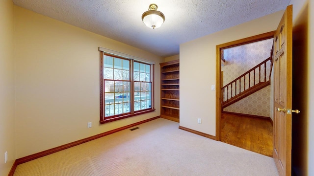 spare room featuring light wood-type flooring and a textured ceiling