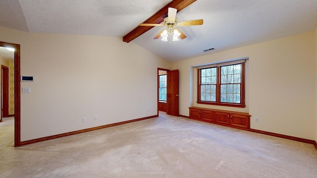 spare room featuring a textured ceiling, lofted ceiling with beams, ceiling fan, and light carpet