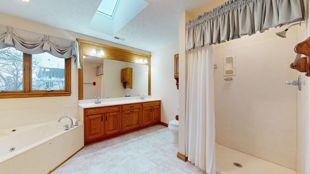 full bathroom with a skylight, separate shower and tub, a textured ceiling, toilet, and vanity