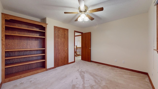 unfurnished bedroom with a textured ceiling, ceiling fan, and light carpet