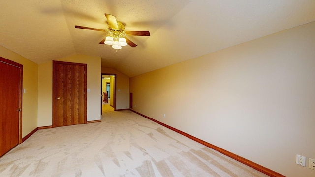 unfurnished bedroom with a textured ceiling, light colored carpet, ceiling fan, a closet, and lofted ceiling