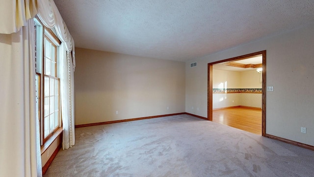 carpeted spare room featuring a textured ceiling