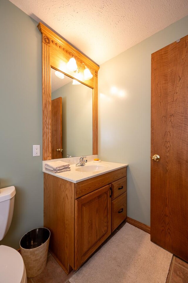 bathroom with vanity, toilet, and a textured ceiling