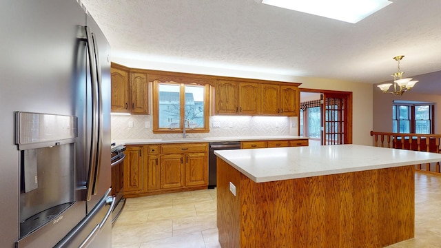 kitchen featuring a wealth of natural light, a kitchen island, stainless steel appliances, and an inviting chandelier