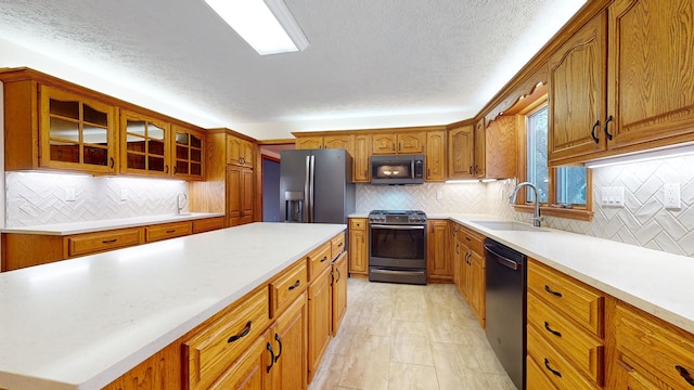 kitchen with decorative backsplash, appliances with stainless steel finishes, a textured ceiling, and sink