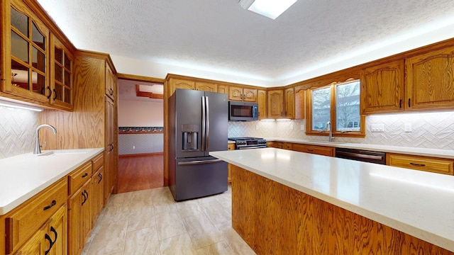 kitchen featuring a textured ceiling, stainless steel appliances, backsplash, and sink